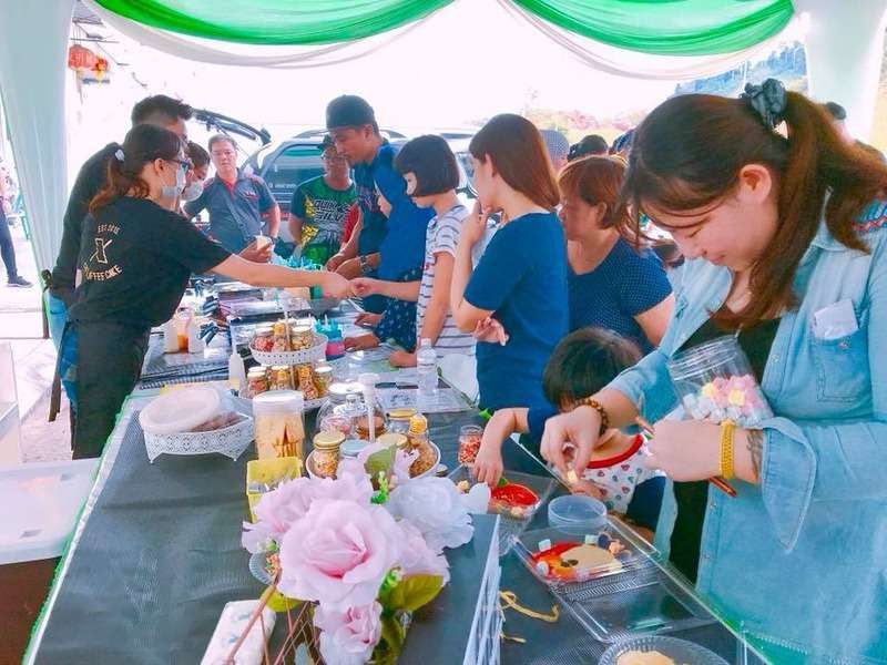 Crew and participants at a long DIY activity table with materials at a Hari Raya event