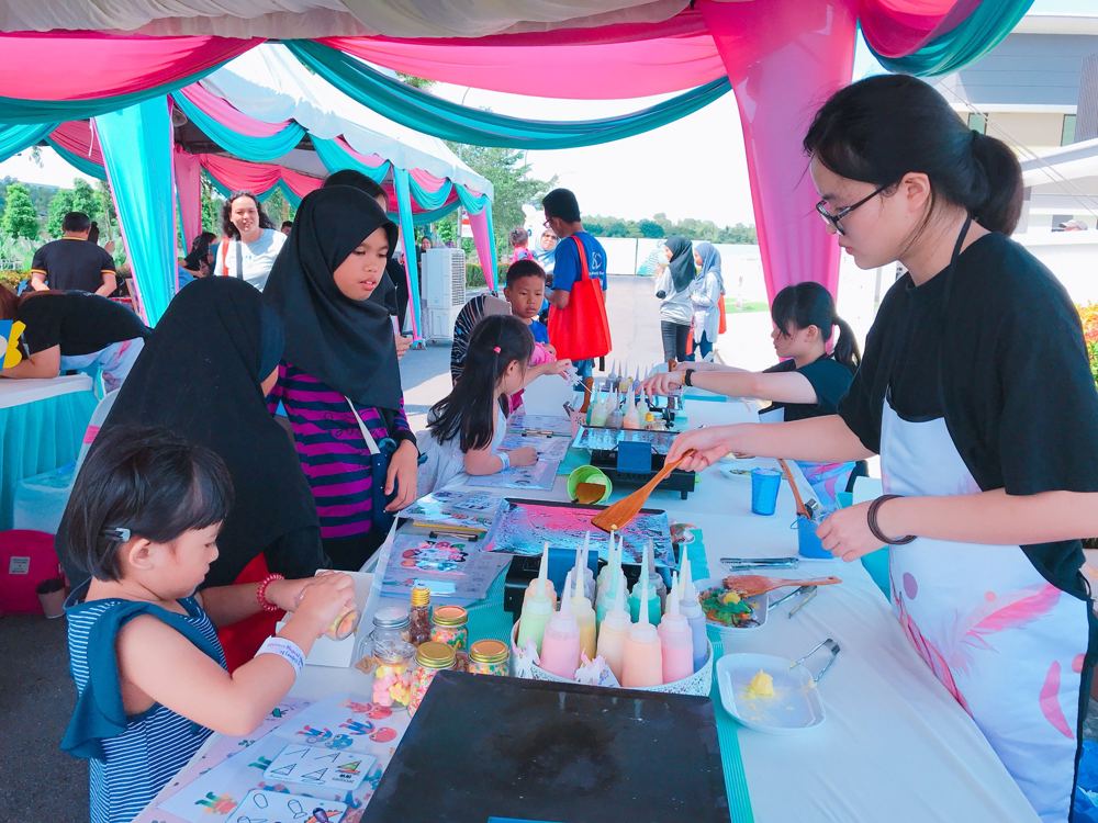 Children and parents making DIY pancakes at a decorated outdoor table while crew help